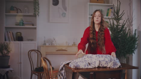 young woman putting tablecloth on table