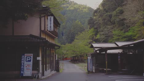 serene view of a deserted street lined with buildings and trees in takaosan, japan. the afternoon light casts a peaceful atmosphere, complemented by a visible parking sign and lush greenery.