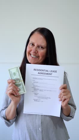 vertical shot of a woman holding a residential lease agreement and cash