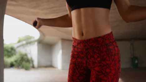 Mid-section-of-young-African-American-woman-exercising-with-skipping-rope-in-the-city-4k