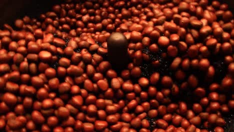 chestnuts being roasted in an automatic electric chestnut roaster machine in yaowarat road or chinatown in bangkok, thailand