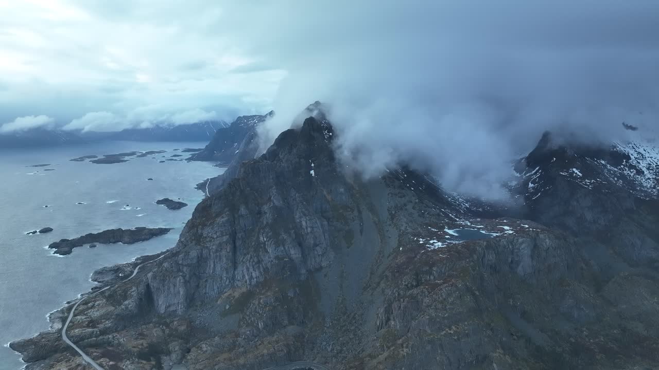 volando sobre extremos picos nebulosos de las montañas reine con vistas al pintoresco océano azul invernal