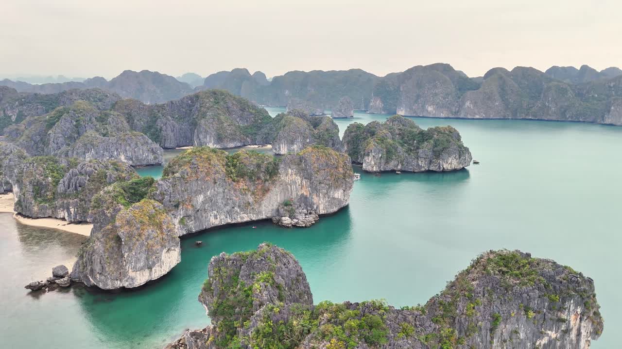Turquoise waters surround towering limestone islands in Ha Long Bay, Vietnam, flying over the limestones