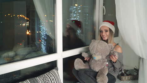 woman with teddy bear by the window at christmas time