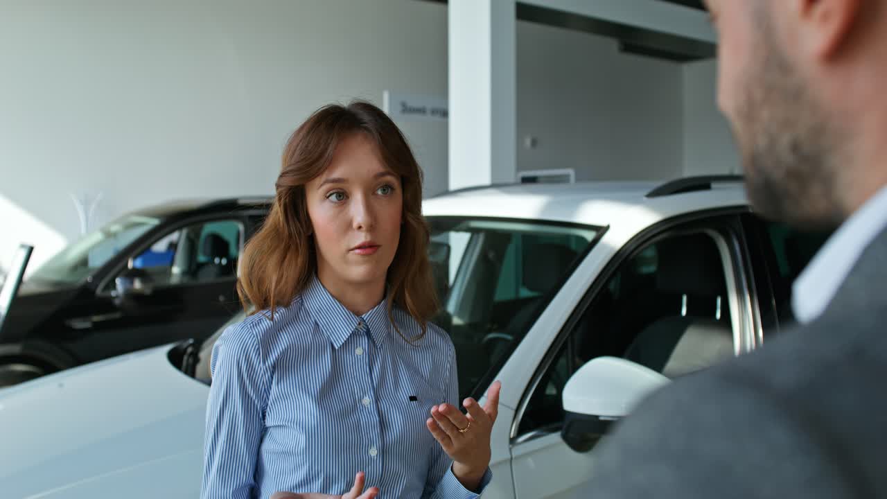 vendedor de automóviles discutiendo un vehículo con un cliente en una sala de exposiciones