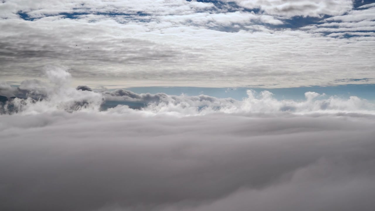 Aerial View of Dense Clouds Moving Over Mountain Landscape