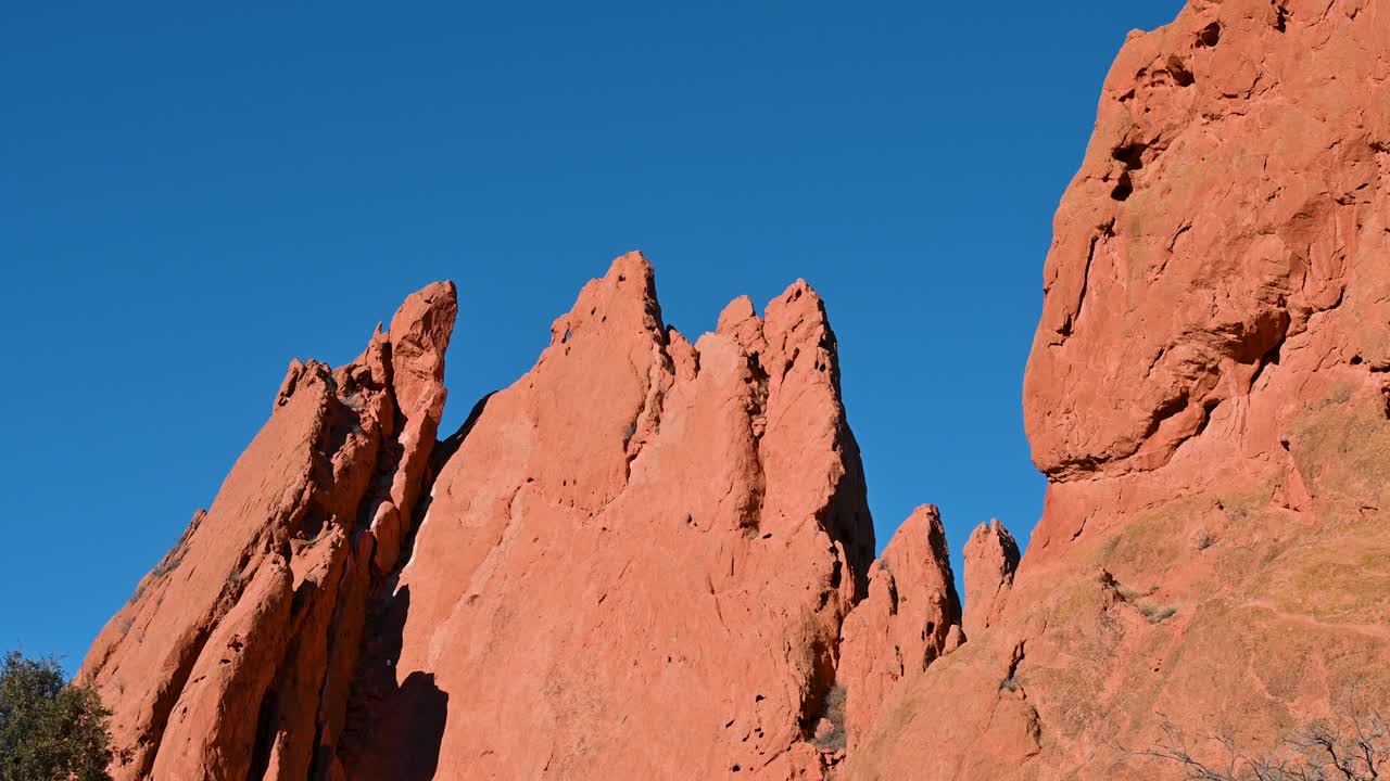 Dramatic drone view of the jagged red sandstone formations at Garden of the Gods against a vivid blue sky in Colorado Springs