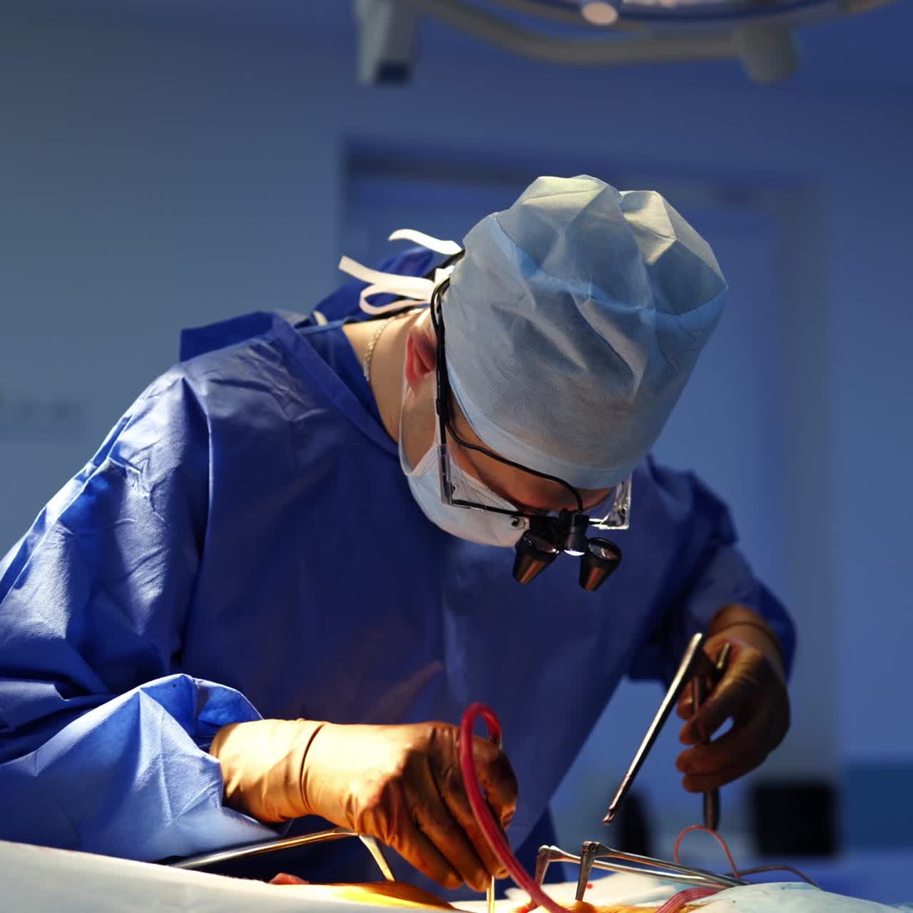 Professional doctor uses surgical tools during operation. Neurosurgeon in medical uniform wearing glasses with microscope lenses while performing a surgery