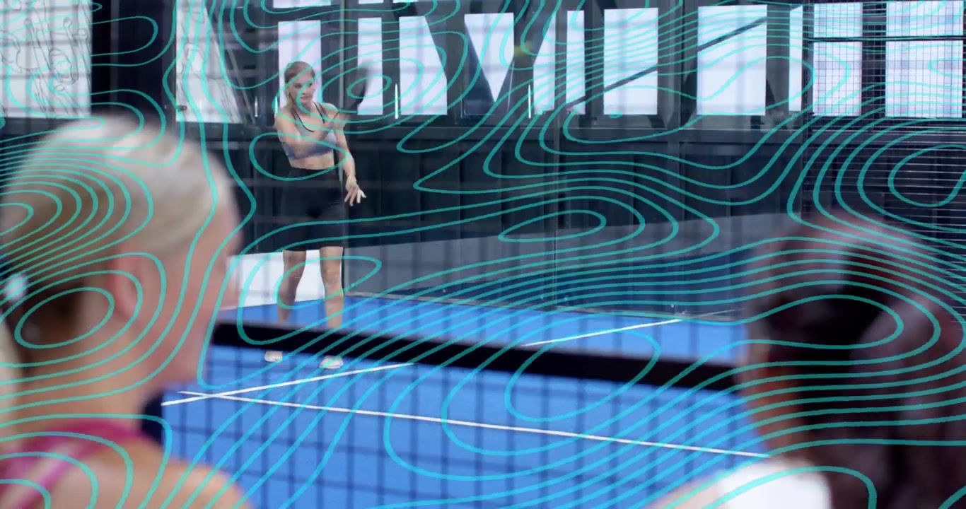 Coach tossing ball during practice, active player executing forehand swing over net on padel court