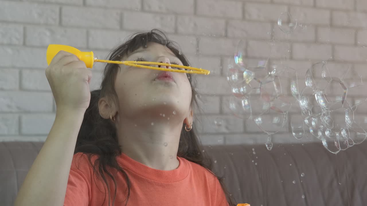 Child blowing soap bubbles indoor.