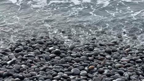 sea water waves into rocky pebble stone beach, relaxing calming in tenerife