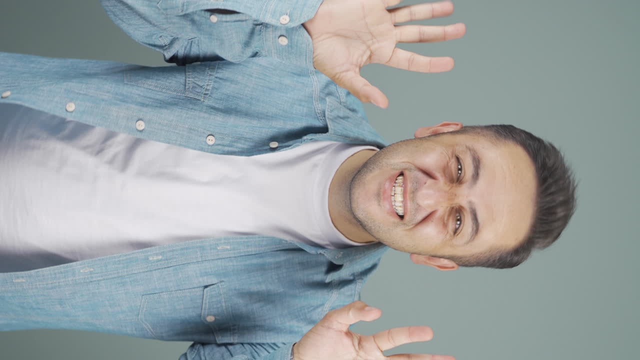 카메라를 위해 귀여운 몸짓을 하는 남자의 수직 비디오.