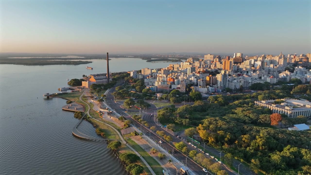 Scena aerea introduttiva dello skyline della città di Porto Alegre e del parco fluviale all'ora d'oro.