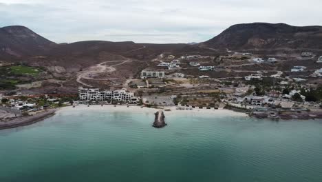 aerial view of the wonderful playa el caymancito during a summer trip through baja california sur mexico with view of the beautiful beach, hotel buildings and dry landscape with mountains