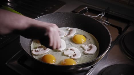 eggs with slices of mushrooms cooking in a pan, adding chopped avocado fruit