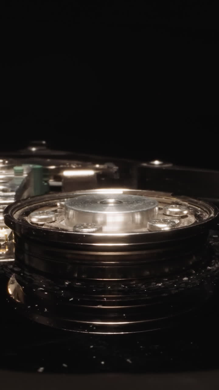 Open hard disk drive with shiny head reflecting bright light on dark background. Modern non-volatile data storage device used for computers macro