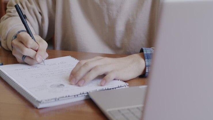 Person working on a laptop and taking notes