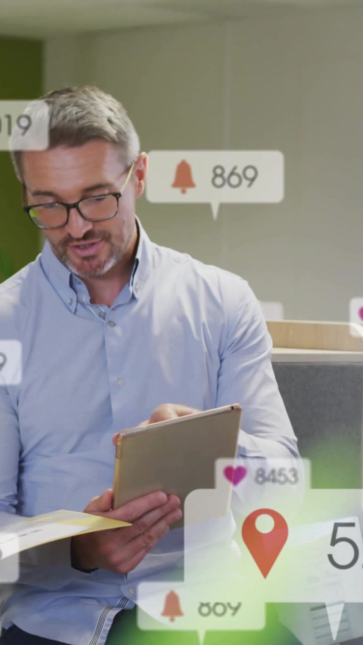 Vertical video: Man tapping tablet and docs, updating icon badges for business while glancing left