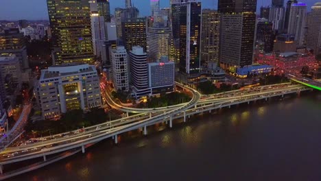 forward aerial view of a modern city center with highway along riverside at night