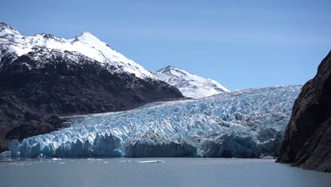 Turismo-Glaciar-En-Un-Lago-Con-Una-Montaña-Con-Nieve-En-La-Parte-Superior-En-El-Fondo