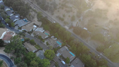 Aerial-of-neighborhood-houses-and-street-nestled-in-a-valley-between-mountains