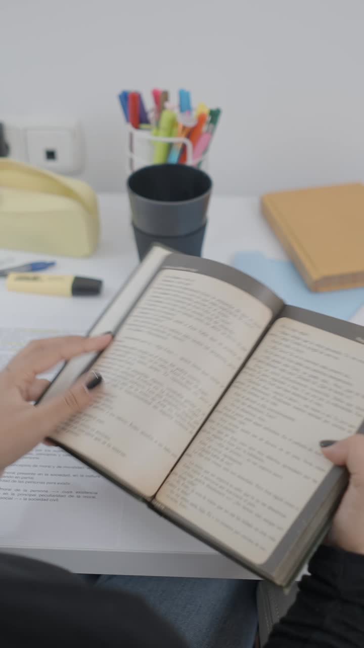 Person Opening and Reading a Book on a Desk