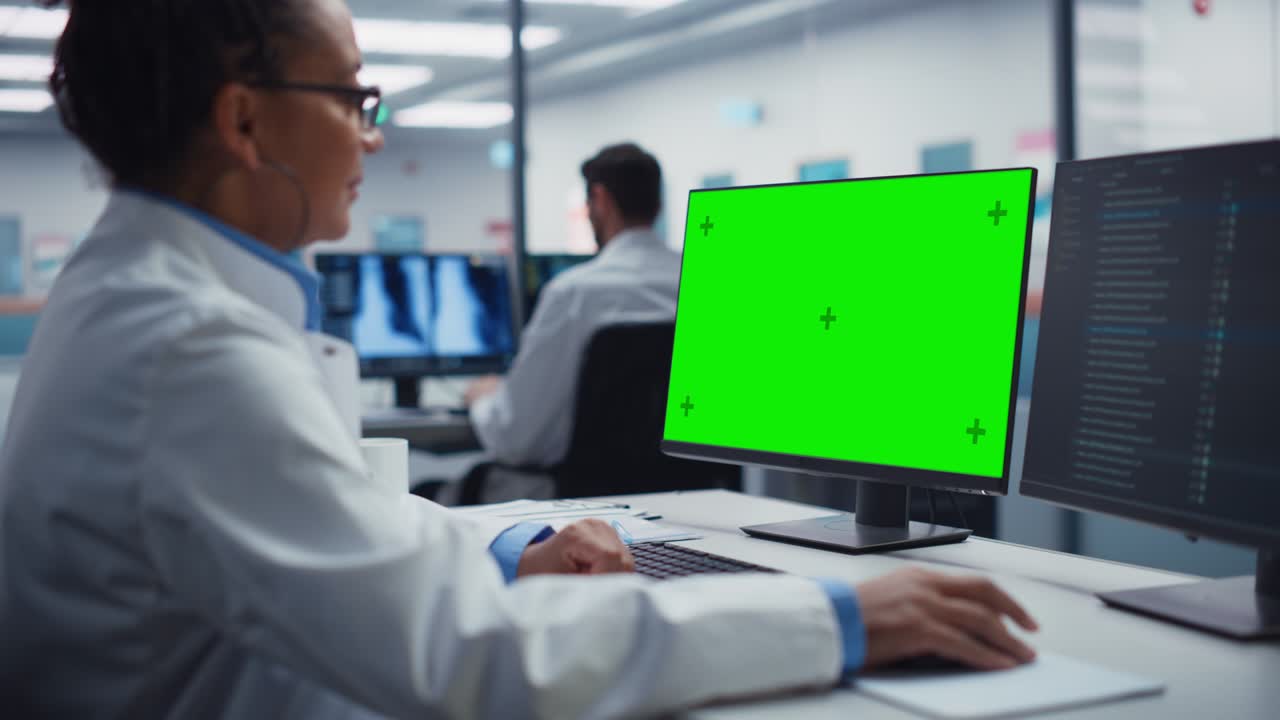 dottore medico donna nera sta lavorando su un computer con schermo verde in un ospedale. professionale scientifico afroamericano che fa ricerca di trattamento biotecnologico in un moderno ospedale