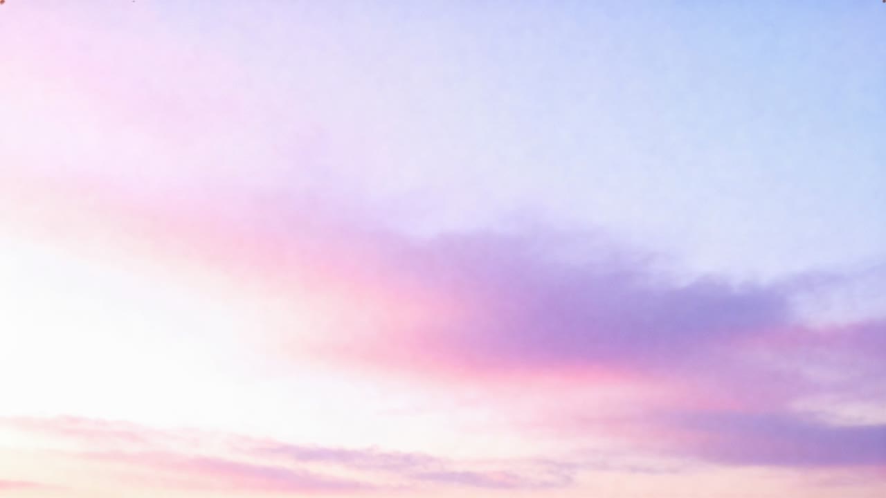 Drifting wide soft pink-purple cloud band shifting over sunrise sky, off-frame sunlight appearing