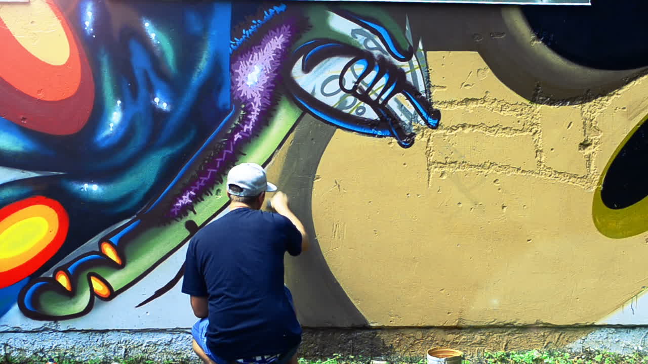 L'artista realizza graffiti su una recinzione. Disegno astratto
