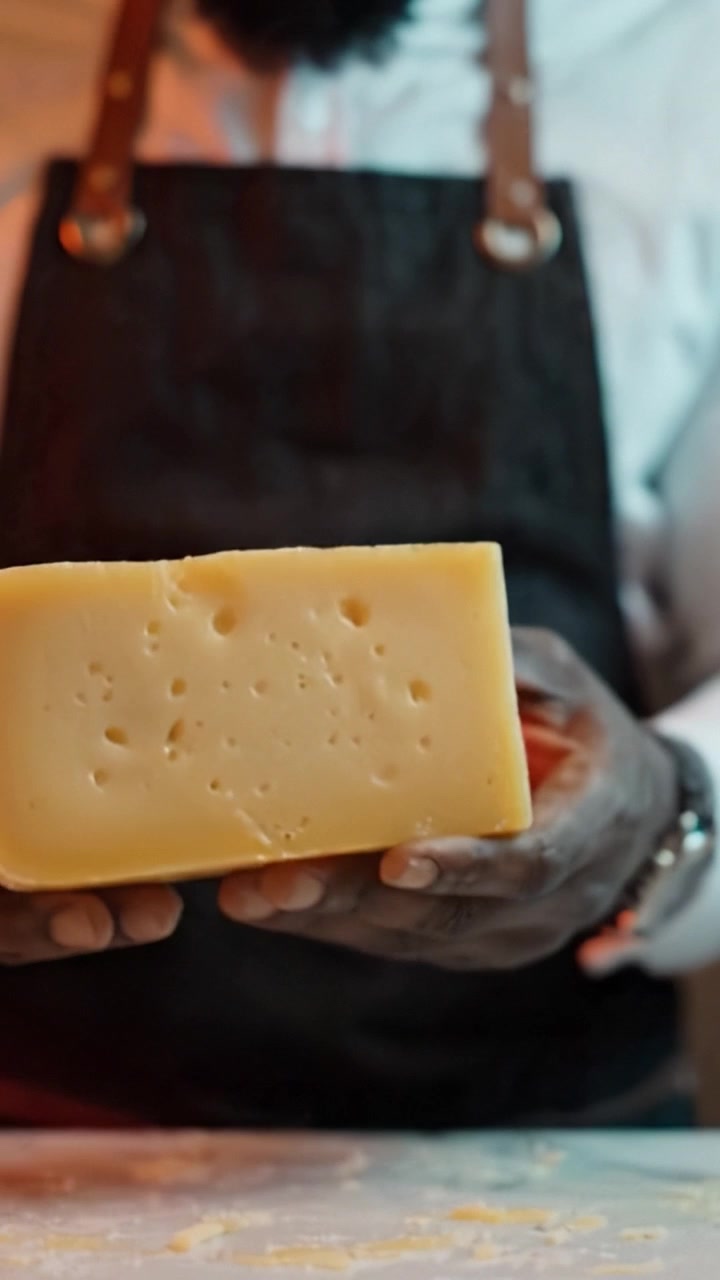 Uno chef esperto che prepara formaggio gourmet con precisione e cura, mostrando l'arte della maestria culinaria in un ambiente di cucina professionale.