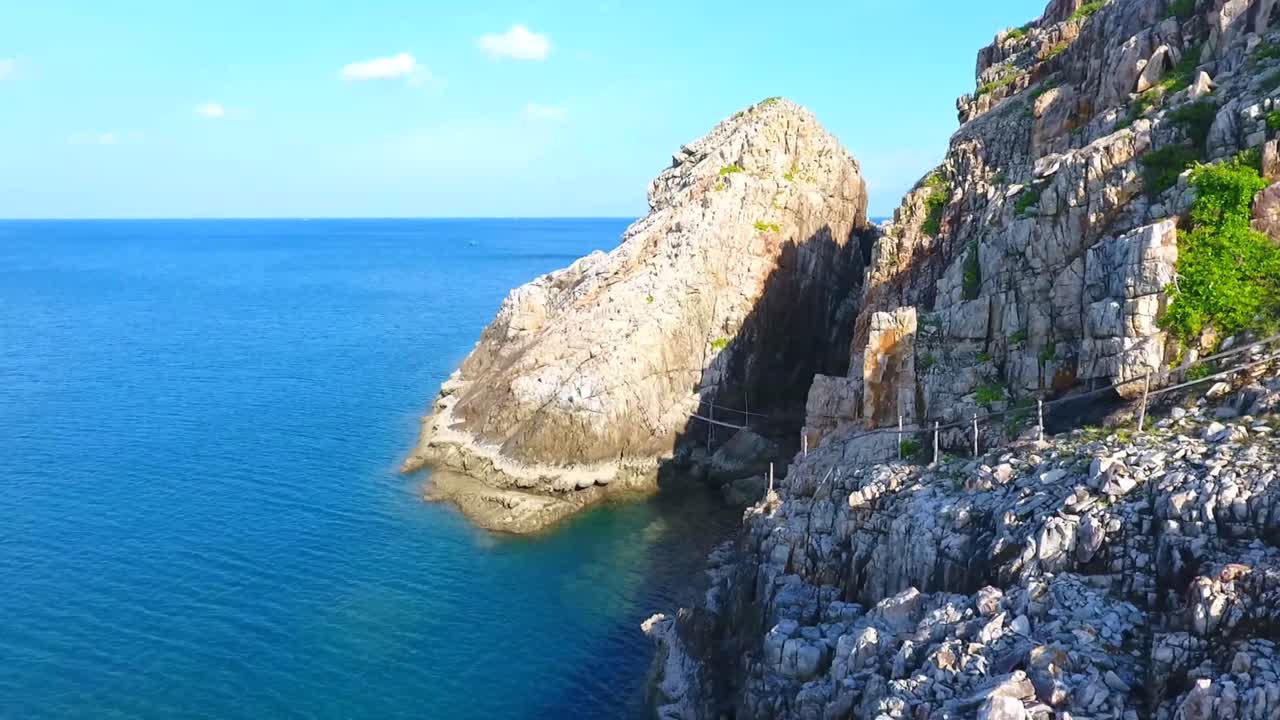 Vista aerea con drone di una costa rocciosa frastagliata con scogliere a picco che incontrano l'acqua cristallina dell'oceano, creando un paesaggio costiero spettacolare sull'isola di Ly Son nel Vietnam centrale