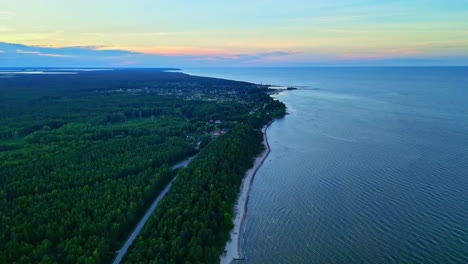 Statischer-Drohnenflug-über-Einem-Langen-Strand-Am-Meer-Und-Einem-Großen-Wald-An-Einem-Wolkenlosen-Tag-Mit-Atemberaubenden-Farben-Am-Horizont,-Kopierraum