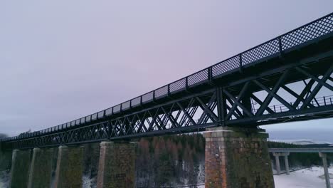 looking over findhorn viaduct towards forest and winter landscape with icy river