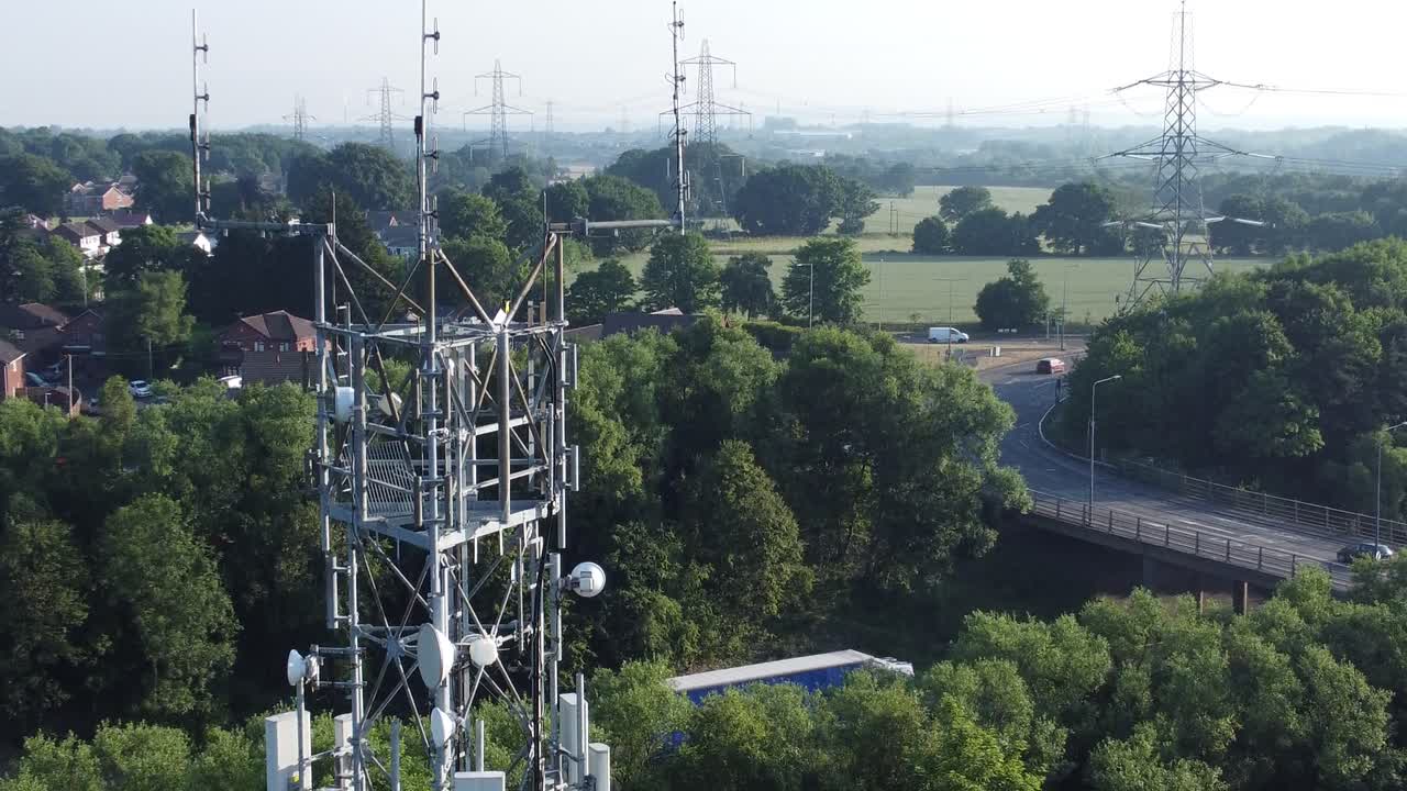 antena de torre de señal 5g en la campiña británica con vehículos que viajan por el fondo de la autopista vista aérea descendente cercana