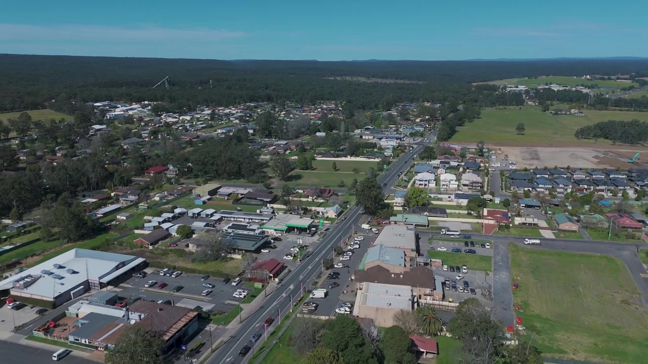 Ripresa aerea in allontanamento della città di Appin, Australia, che mostra aree residenziali, spazi verdi e il paesaggio circostante attraversato da strade