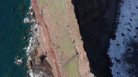 People-hiking-on-thin-mountain-range-cinematic-with-ocean-on-each-side-during-sunny-day