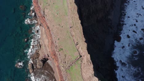 gente caminando en una delgada cordillera cinematográfica con el océano a cada lado durante un día soleado