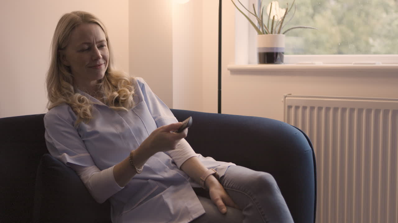 Kvinde ser tv på sofaen