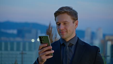 A man's plain expression turns to happiness as he gets good news on his phone and nods for success, captured in a slow-motion parallax shot on a Seoul rooftop at sunset