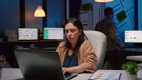 workaholic tired businesswoman typing financial statistics on laptop