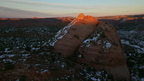 Drone-shot-rising-up-to-view-red-rock-formation-in-dramatic-dusk-light