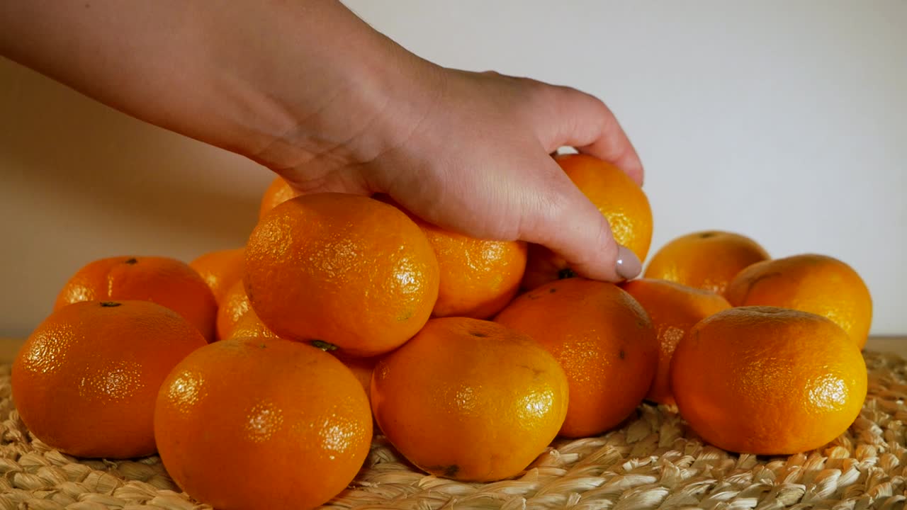 la hermosa mano femenina está poniendo una naranja en el montón de naranjas