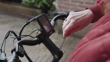señora ajustando un perno de llave allan para poder cambiar el ángulo del manillar de su bicicleta eléctrica