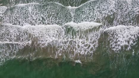 aerial: top down shot of long ocean waves reaching the shore in southern thailand