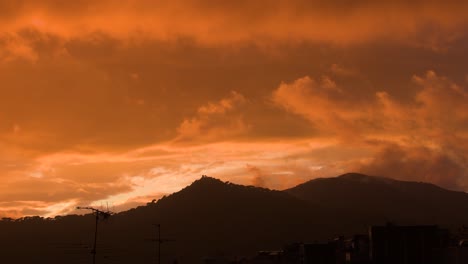 Blick-Auf-Ferne-Berge-In-Einem-Orangefarbenen-Sonnenuntergang,-Während-Sich-Am-Himmel-Die-Wolken-Langsam-Bewegen