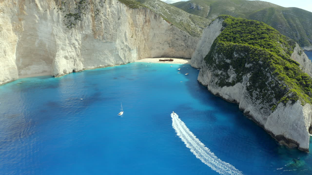 un recorrido en barco acercándose a la playa de naviago desde una toma aérea de drones en zakynthos, grecia