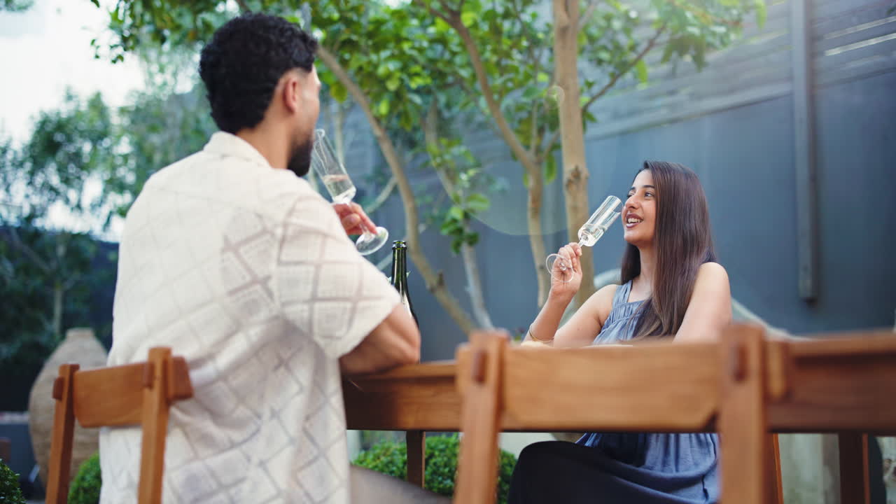 Coppia felice che brinda con champagne su un patio esterno.