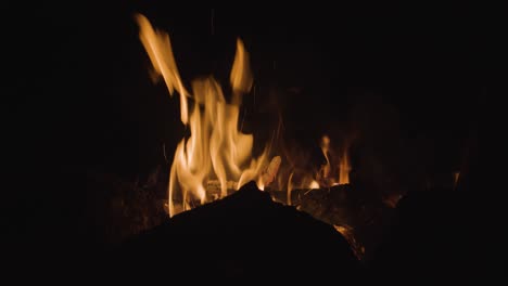 a warm campfire is burning bright at night with the silhouette of rocks in front of it