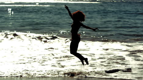 Mujer-Saltando-Y-Levantando-Brazos-Y-Piernas-En-El-Mar