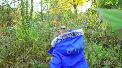 Following-a-curious-little-girl-as-she-wanders-through-a-forest-and-along-a-stream-on-a-cool,-autumn-day